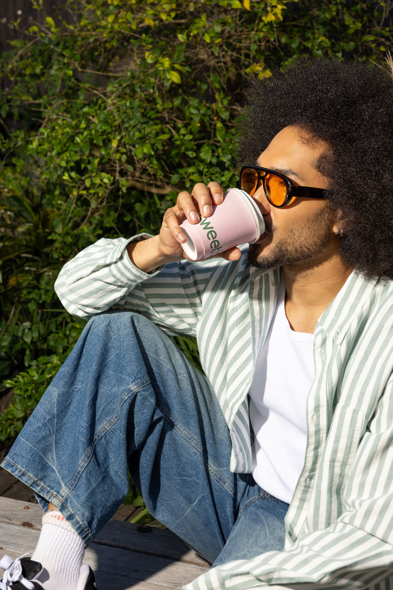 A customer sitting in the sun with a pink Sweetbeet coffee cup